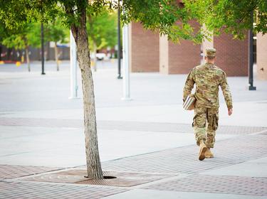 A soldier walks on a college campus