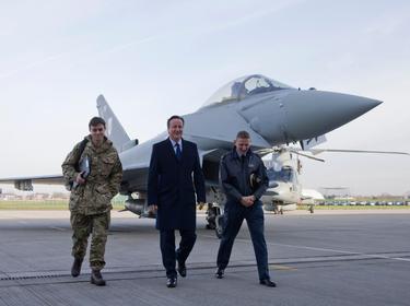 Britain's Prime Minister David Cameron (C) walks with Group Captain David Manning (R) past an RAF Eurofighter Typhoon fighter jet at Royal Air Force station RAF Northolt in London, November 23, 2015