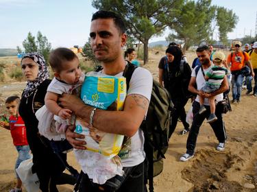 Syrian refugees walk towards a crossing point at Greece's border with Macedonia, September 8, 2015