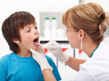 doctor checking the throat of a young boy