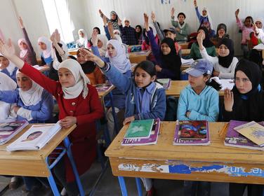 Syrian refugee students raise their hands as they attend class in a UNICEF school at the Al Zaatari refugee camp, Jordan, March 11, 2015