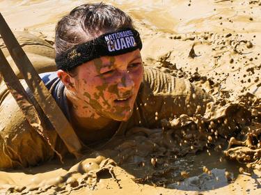 2nd Lt. Mary Kauffman, Ohio Army National Guard, crawls through mud during the Warrior Dash Aug. 11, 2013, in North Lawrence, Ohio