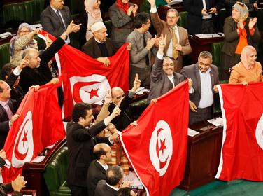 Members of the Tunisian parliament wave flags after approving the country's new constitution in Tunis, January 26, 2014
