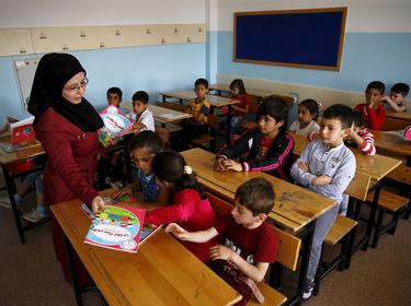 A Syrian refugee teacher distributes books to her refugee students in the Karapurcek district of Ankara, Turkey