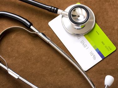A stethoscope rests on a credit card.