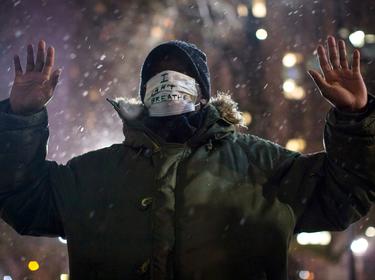 A man holding a 'Hands Up, Don't Shoot' pose and wearing an 'I Can't Breathe' mask outside City Hall, New York City, December 10, 2014