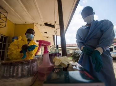 Medical staff put on protective gear before taking a sample from a suspected Ebola patient in Kenema, Sierra Leone, July 10, 2014