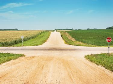 An intersection of gravel roads through a field
