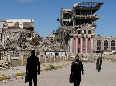 People walk in front of the remains of the University of Mosul, which was burned and destroyed during a battle with Islamic State militants, in Mosul, Iraq, April 10, 2017.