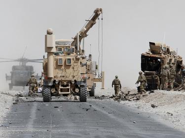 U.S. troops assess the damage to an armored vehicle of the NATO-led military coalition after a suicide attack in Kandahar province, Afghanistan, August 2, 2017