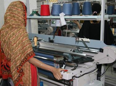 Woman working a flat-knit machine, photo by Cross Design/Adobe Stock