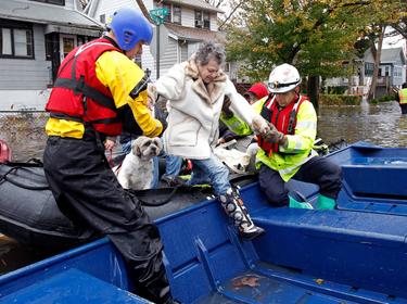 Emergency personnel help a resident onto a boat after rescuing her from flood waters brought on by Hurricane Sandy in Little Ferry, New Jersey, October 30, 2012, photo by Adam Hunger/Reuters 