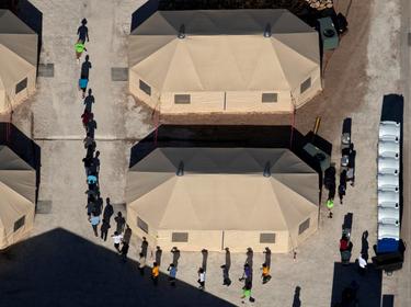 Immigrant children are led by staff in single file between tents at a detention facility near the Mexican border, Tornillo, Texas, June 18, 2018, photo by Mike Blake/Reuters