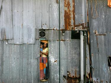 A woman holding a baby looks out of a window from a shanty in Dharavi, Mumbai, India, October 15, 2009, photo by Arko Datta/Reuters