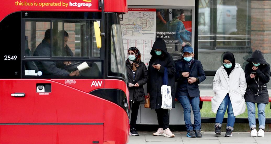 People wearing protective face masks wait for a bus in front of St. Paul's Cathedral in London, Britain, March 19, 2020, photo by Simon Dawson/Reuters