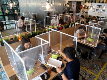 People have lunch at a restaurant that reopened with plastic barriers and social distancing measures to prevent the spread of COVID-19 in Bangkok, Thailand, May 8, 2020, photo by Athit Perawongmetha/Reuters