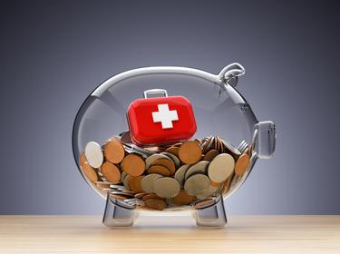 Clear piggy bank with coins and red medical case, photo by Altayb/Getty Images
