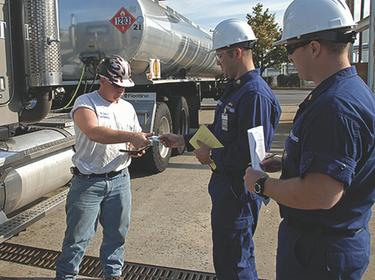 A truck driver shows his transportation worker identification credentials to Coast Guard Petty Officer 1st Class Kevin Parrington and Ens. Cassidy Childs at the Motiva Enterprises fuel terminal. Photo by PA2 Lauren Jorgensen/Coast Guard First District Public Affairs
