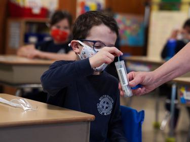 A child places his COVID-19 testing swab in a vial at South Boston Catholic Academy in Boston, Massachusetts, January 28, 2021, photo by Allison Dinner/Reuters