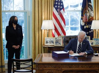 President Joe Biden signs the American Rescue Plan with Vice President Kamala Harris looking on, in the Oval Office at the White House in Washington, D.C., March 11, 2021, photo by Tom Brenner/Reuters