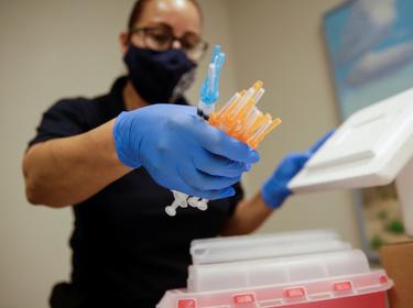 A healthcare worker holds syringes with COVID-19 vaccines at a vaccination center, in El Paso, Texas, May 6, 2021, photo by Jose Luis Gonzalez/Reuters
