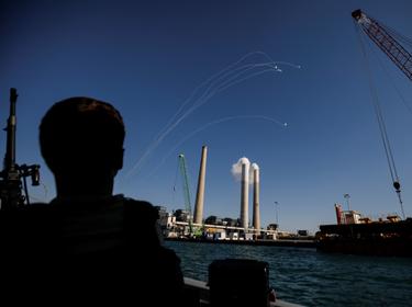 An Israeli soldier watches as Israel's Iron Dome anti-missile system intercept rockets launched from the Gaza Strip towards Israel, off the southern Israeli coast, May 19, 2021, photo by Amir Cohen/Reuters