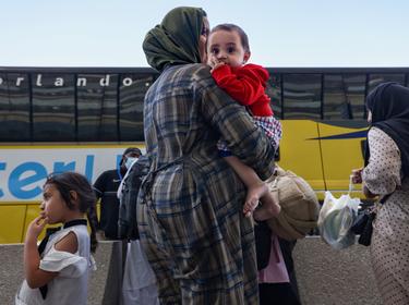 Afghan refugees board buses that will take them to a processing center after arriving at Dulles International Airport in Dulles, Virginia, September 2, 2021, photo by Evelyn Hockstein/Reuters