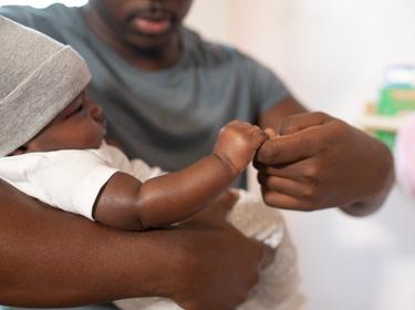 A young Black man holding his infant child, photo by NappyStock