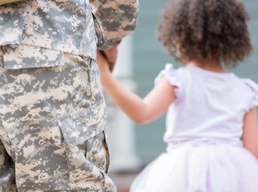 Close up from behind of a little girl holding her soldier parent's hand, photo by SDI Productions/Getty Images
