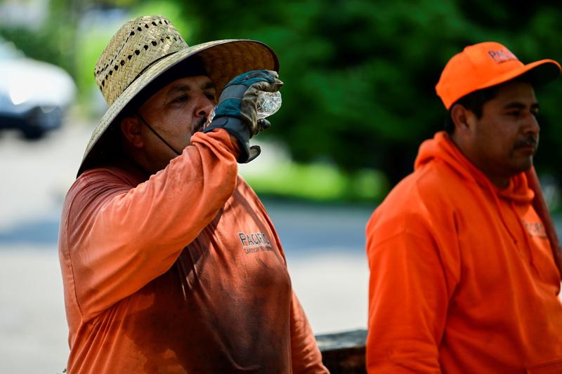 Aureliano Dominguez drinks water after finishing a landscaping job as a heat wave continues in Portland, Oregon, August 12, 2021, photo by Mathieu Lewis-Rolland/Reuters