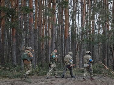 Ukrainian service members walk on the front line near Kyiv as Russia's invasion of Ukraine continues, Ukraine, March 30, 2022, photo by Gleb Garanich/Reuters