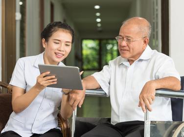 Woman using a digital tablet with an elderly man