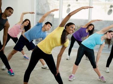 A group of young adults stretching in a dance class