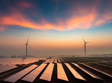 Solar and wind farm with sunset and clouds, photo by yangphoto/Getty Images