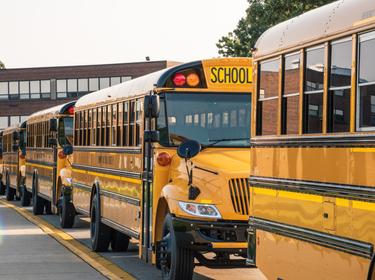 Yellow school busses lined up outside a school, photo by DavidPrahl/Getty Images