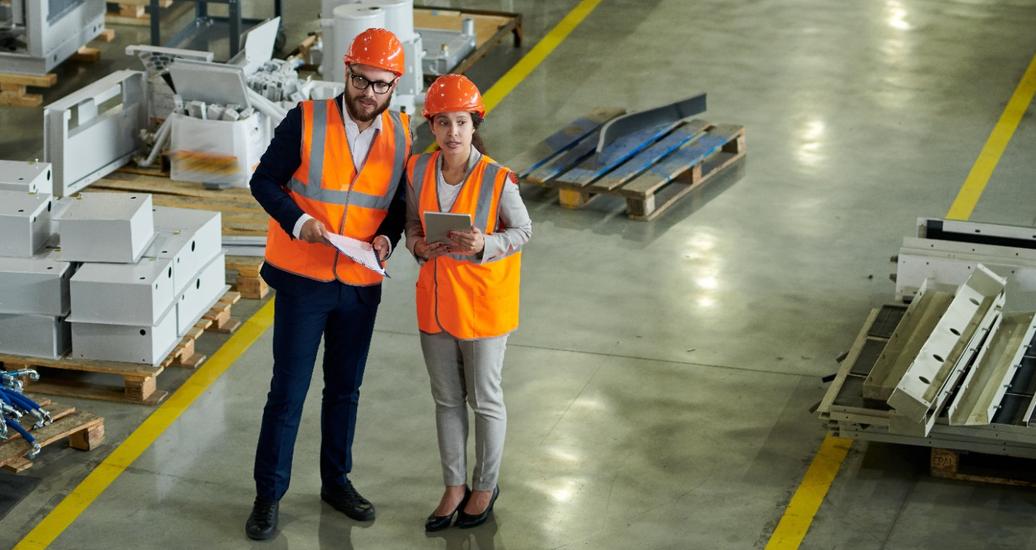 High angle portrait of two business people wearing hardhats, inspecting production workshop, photo by 