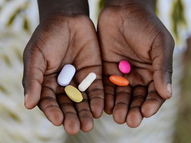 African male holding pills, photo by Riccardo Mayer/Adobe Stock