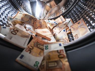 Euro banknotes spilling out of a washing machine, photo by ronstik/Getty Images