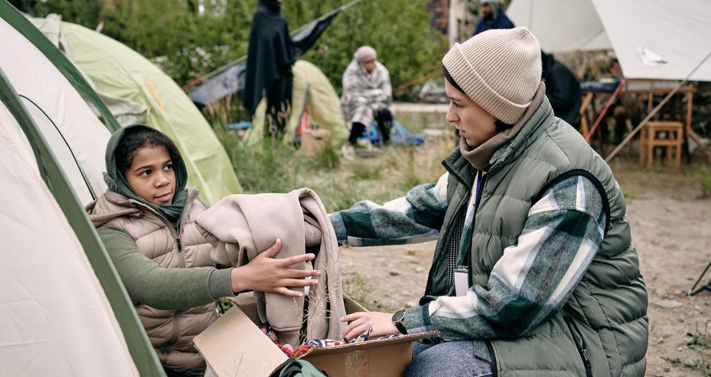 A woman giving clothes to a child who is homeless, photo by shironosov/Getty Images