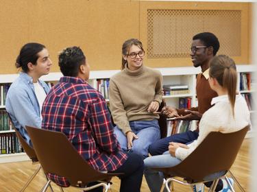 Multi-ethnic group of young people sitting in circle and sharing ideas during class in college, photo by Seventyfour/Adobe Stock